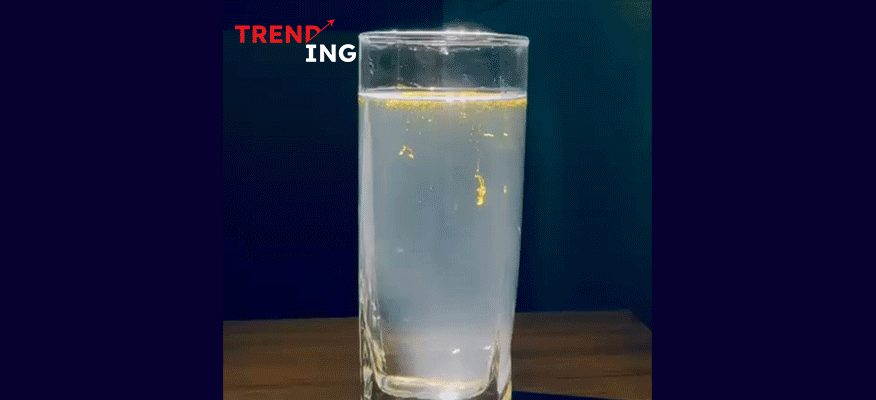 A glass of glowing turmeric water with gold like flakes