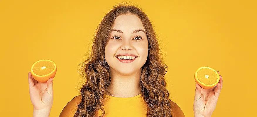 teen-girl-holding-orange-fruit-rich-in-vitamin-C-for-teenagers