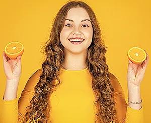 teen-girl-holding-orange-fruit-rich-in-vitamin-C-for-teenagers