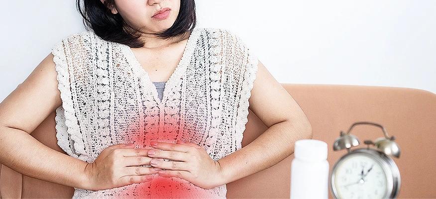 Young woman holding stomach in discomfort, feeling bloated and gassy