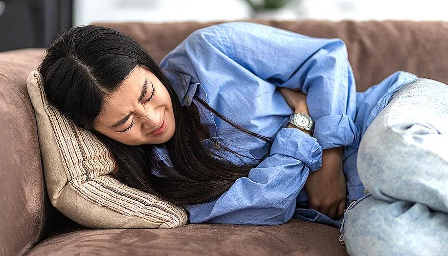 Woman lying on couch with stomach pain