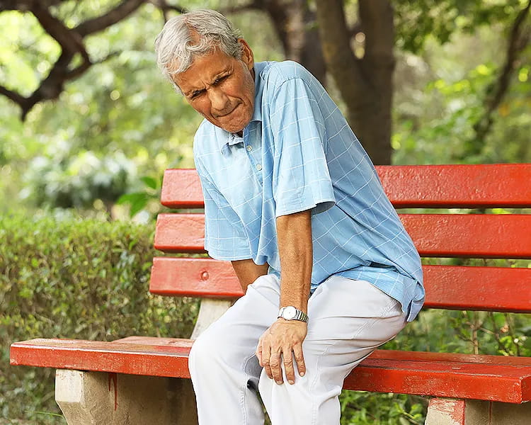 Senior holding knee in pain due to age-related joint issues like arthritis