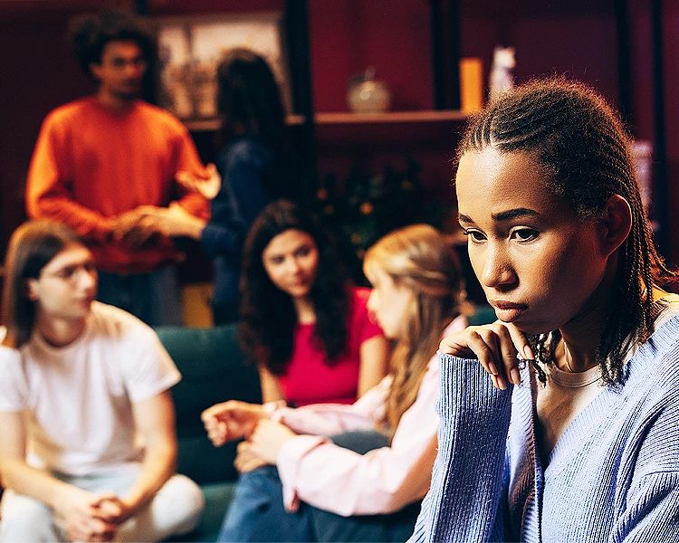 Young woman feeling isolated in social gathering showing social anxiety symptoms and emotional distress