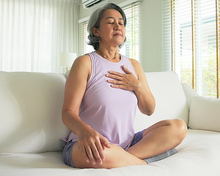 Woman practicing deep breathing exercise at home to reduce stress and anxiety naturally