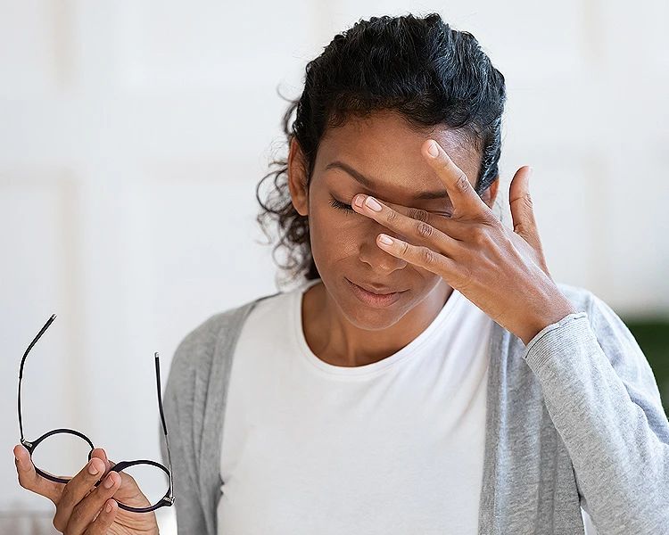 Woman experiencing anxiety disorder symptoms holding glasses and feeling stressed